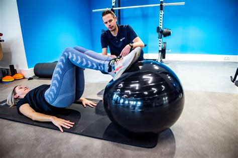 Een persoon die oefeningen doet onder begeleiding van een fysiotherapeut in een moderne fitnessruimte.