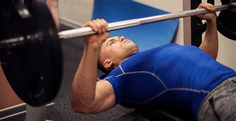 Man die bankdrukken uitvoert op een fitnessbank