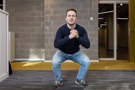 Man die een squat uitvoert met een bal tegen zijn rug en een elastische band