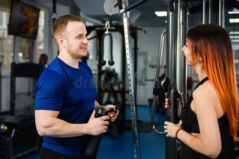 Personal trainer die een klant begeleidt in een moderne gym