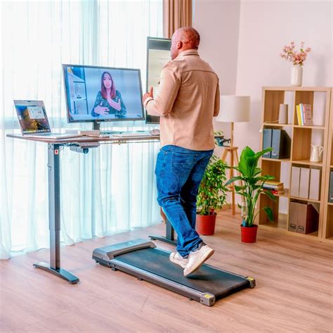 Een persoon die werkt aan een bureau met een Infinity Goods loopband eronder