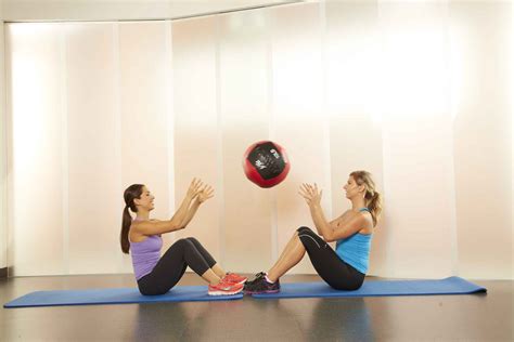 Twee personen doen partner sit-ups met bal